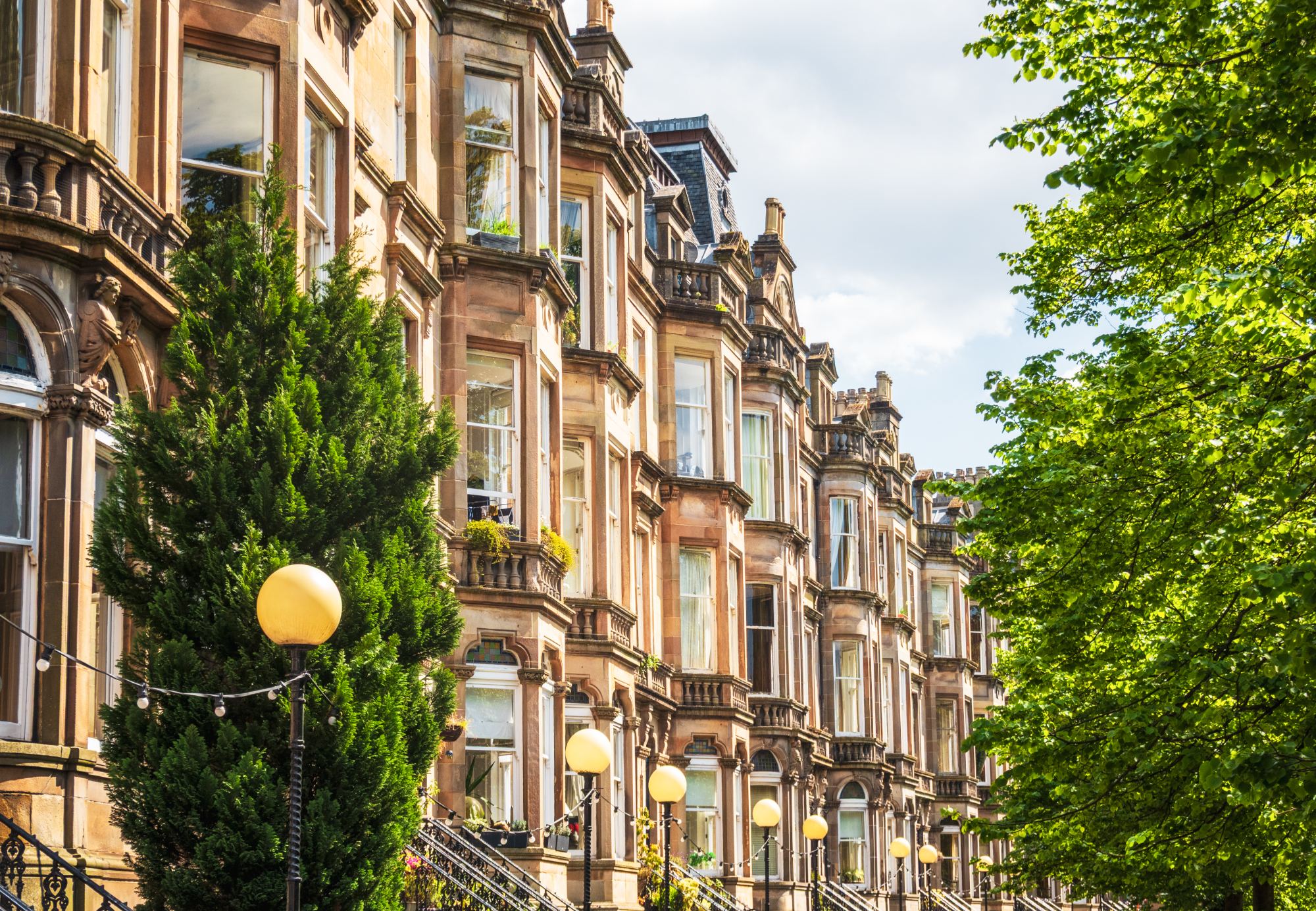 Sunlit sandstone tenement terrace in Glasgow's West End